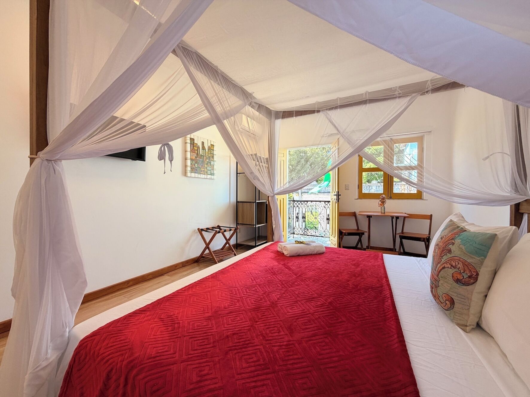 A room with a bed, a table, chairs, and a balcony.