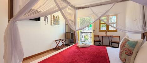 A room with a bed, a table, chairs, and a balcony.