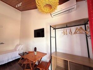 Una habitación con cama, una mesa, un televisor y un perchero.