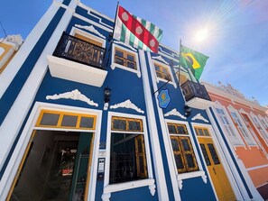 Un edificio con fachada azul, adornos blancos y balcones con barandillas ornamentales.