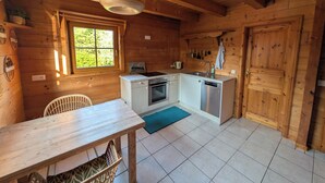 A wooden cabin with a kitchen, dining table, and a window.