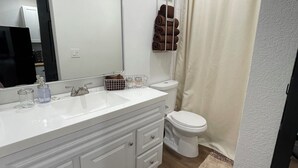 Ein modernes Badezimmer mit einem weißen Waschtisch, einer Toilette und einer Duschvorhang.
