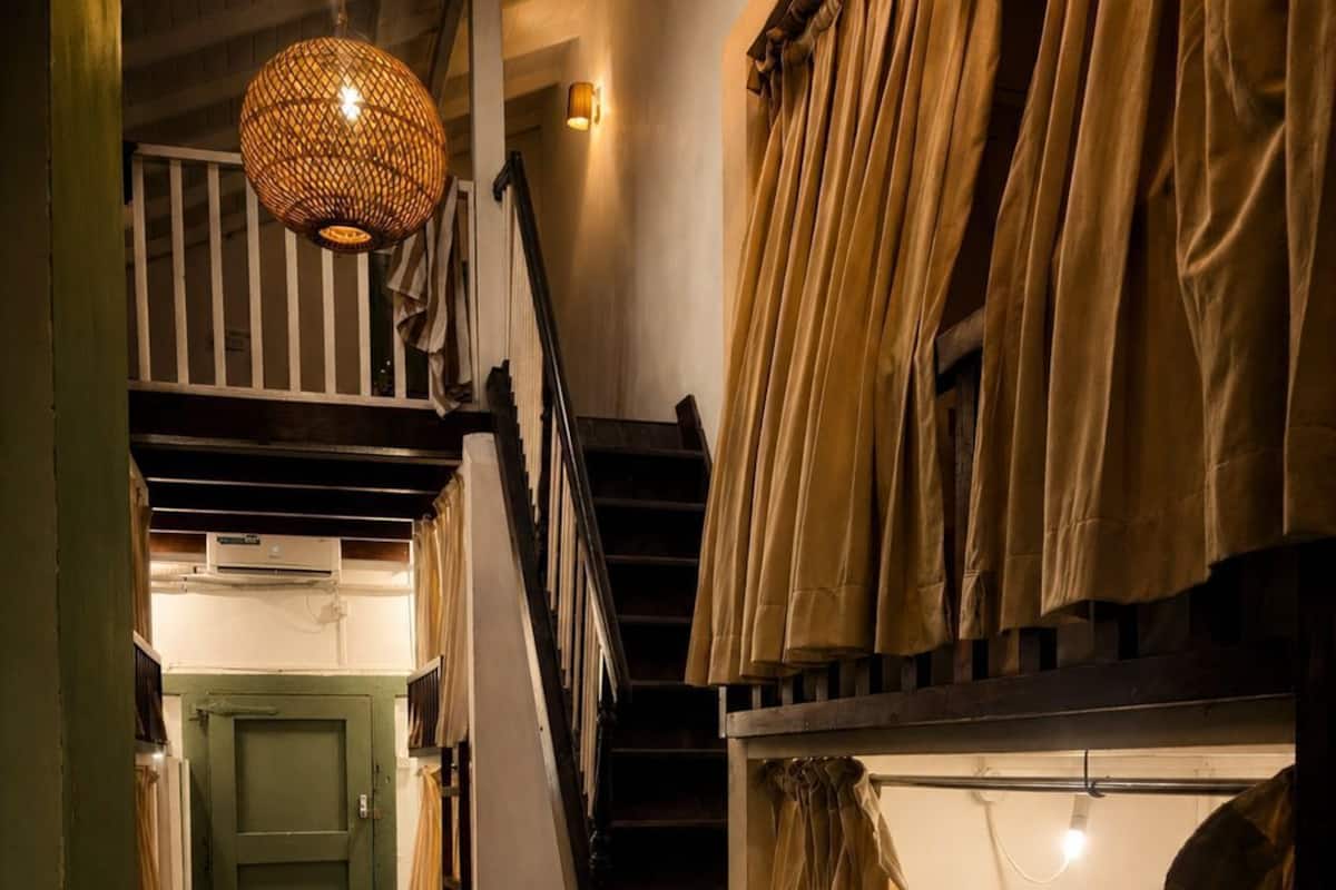 A room with bunk beds, a staircase, a hanging light fixture, and a door.
