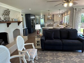 A modern living room with a fireplace, a dark sofa, a white chair, and a patterned rug.