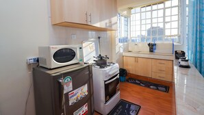 A compact kitchen with a microwave, stove, and refrigerator. - Peaceful 1-bedroom corporate apartment in vibrant Nairobi (Nairobi)