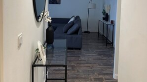Moderni olohuone, jossa on sohva, peili, lamppu ja pieni pöytä.