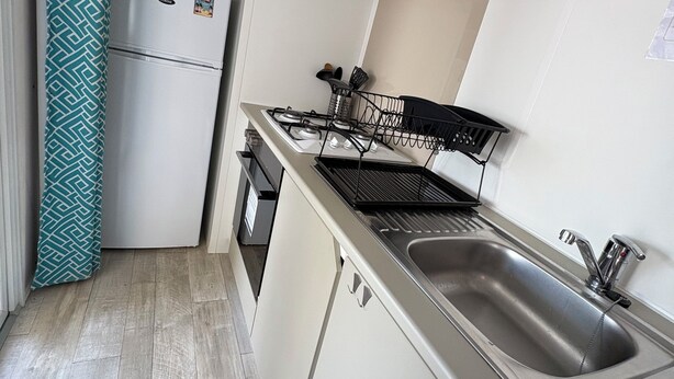 Een kleine keuken met een magnetron, fornuis en spoelbak.