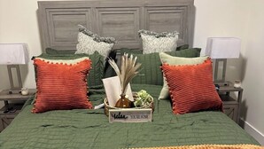 A bed with green bedding, two red pillows, a sign reading 'You're Home,' and a bedside table with a lamp. - LSU BOUND! We are minutes from everything! (Baton Rouge)