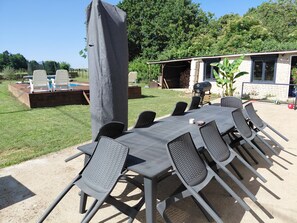 An outdoor patio with a table and chairs, a barbecue grill, and a covered seating area. - Farmhouse in the Heart of Berry (Charentonnay)