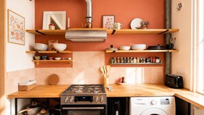 Une cuisine compacte équipée d’une cuisinière à gaz, d’un four et d’un lave-linge encastré.