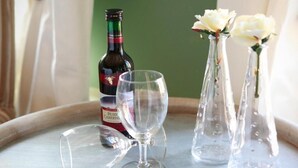 A wine bottle, a wine glass, and two vases with flowers on a tray. - The Abiente Rooms (Bruges)