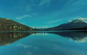Un lago tranquilo con montañas al fondo.