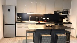 A modern kitchen with a refrigerator, microwave, and coffee maker.