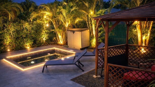 A pool area with a wooden deck, lounge chairs, and a gazebo.
