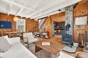 Ein gemütliches Wohnzimmer mit Kamin, Holzwänden, einer Treppe und einem Essbereich.