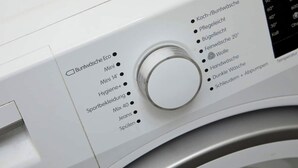 Een wasmachine met een bedieningspaneel waarop verschillende wasprogramma's staan, zoals 'Buntwäsche Eco', 'Mini' en 'Hygiene+'.