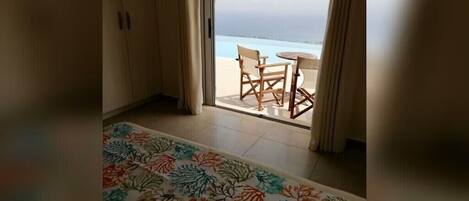 Une pièce avec vue sur la mer, une table en bois avec des chaises et un tapis à motifs floraux.