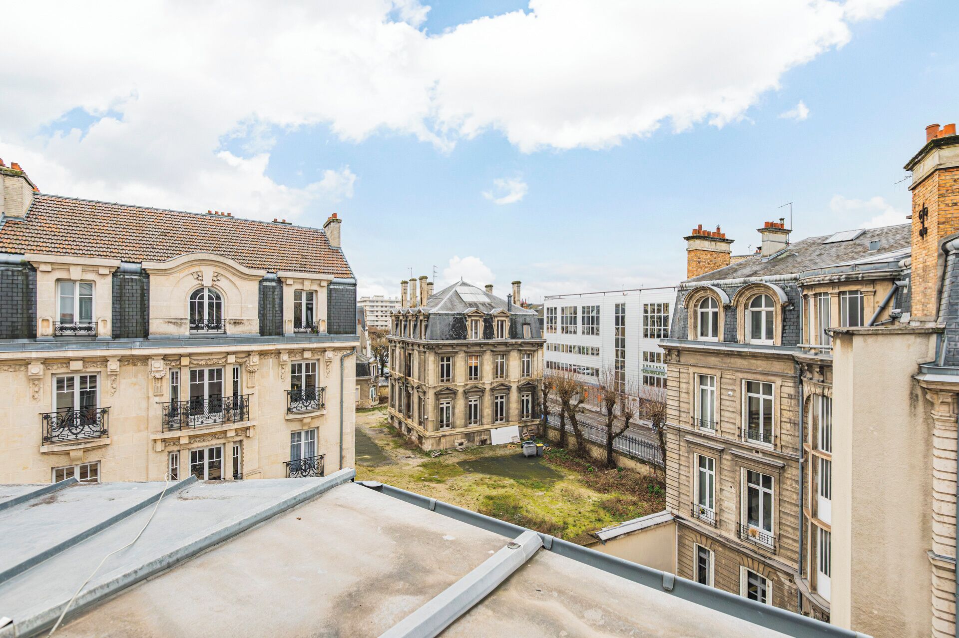 Vista de um pátio cercado por edifícios históricos com sacadas e céu claro.