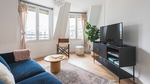 A modern living room with a sofa, TV, and a plant.
