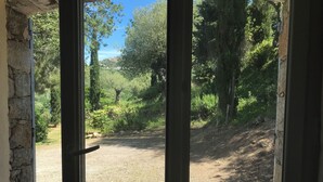 A view through a doorway with a gravel path leading to a forested area. - Charming house in a magnificent park facing the sea and its sunset (Pigna)