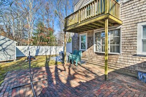 Ein Garten mit Pflasterterrasse, Holzterrasse und weißem Zaun.