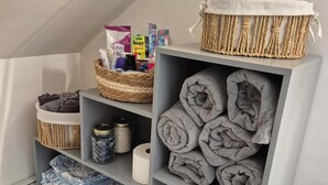 Ein ordentlich eingerichtetes Badezimmer mit Handtuchhalter, Ablagen für Pflegeprodukte und einem gemusterten Boden.