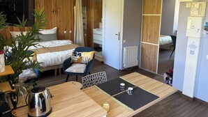 Een kamer met een bed, een stoel, een tafel met waterkoker en een radiator.