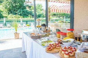 A buffet table with various food items and a pool view. - La Hacienda (Ulcinj)