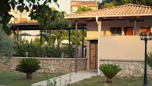 Una casa amb mur de pedra, un porxo cobert i un camí que condueix a l'entrada.