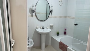 A bathroom with a sink, bidet, toilet, and bathtub.