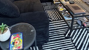 A modern living room with a sectional sofa, a coffee table, a laptop, and a patterned rug. - West LA Wold Cup Hideaway (Los Angeles)