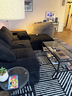 A modern living room with a sectional sofa, a coffee table, a laptop, and a patterned rug. - West LA Wold Cup Hideaway (Los Angeles)