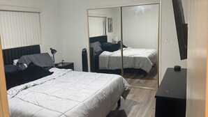 A bedroom with a bed, a mirror, a TV, and a dresser. - West LA Wold Cup Hideaway (Los Angeles)