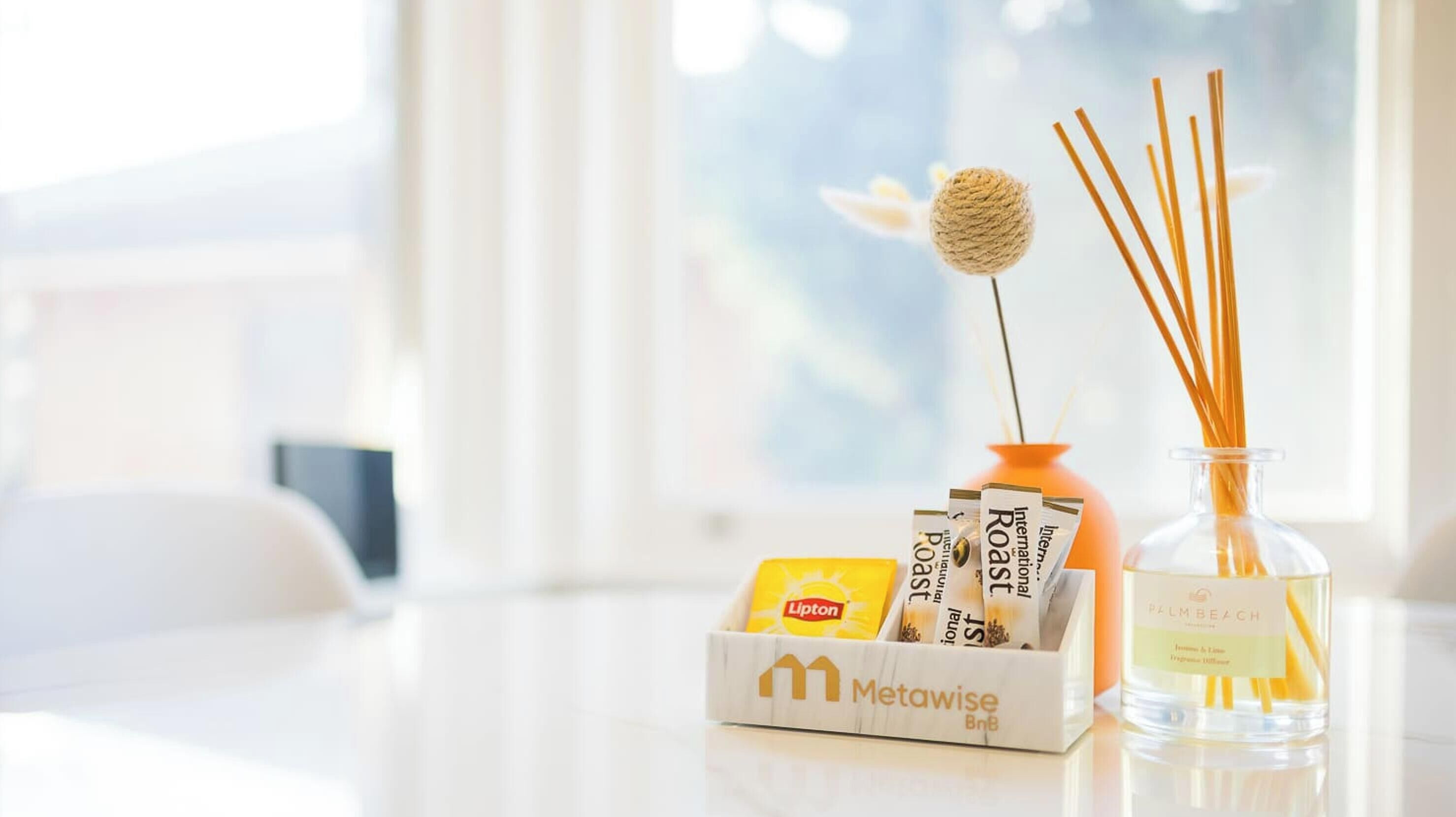 A Metawise branded box with Lipton tea and reed diffuser candles on a table.
