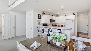 Une cuisine moderne avec des meubles blancs, une table à manger avec des verres à vin et un escalier.