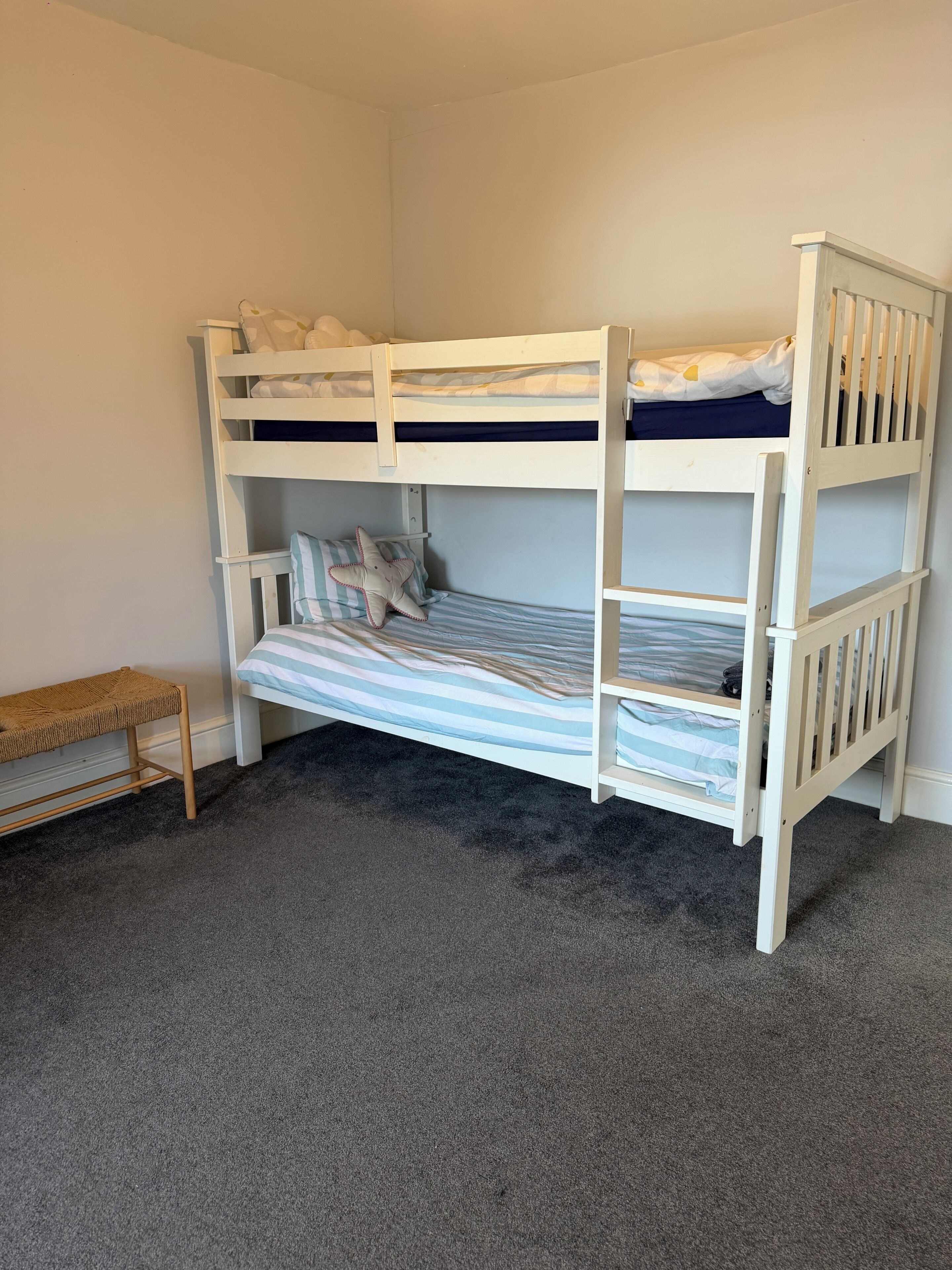 A bunk bed with a bench, a striped pillow, and a starfish decoration.