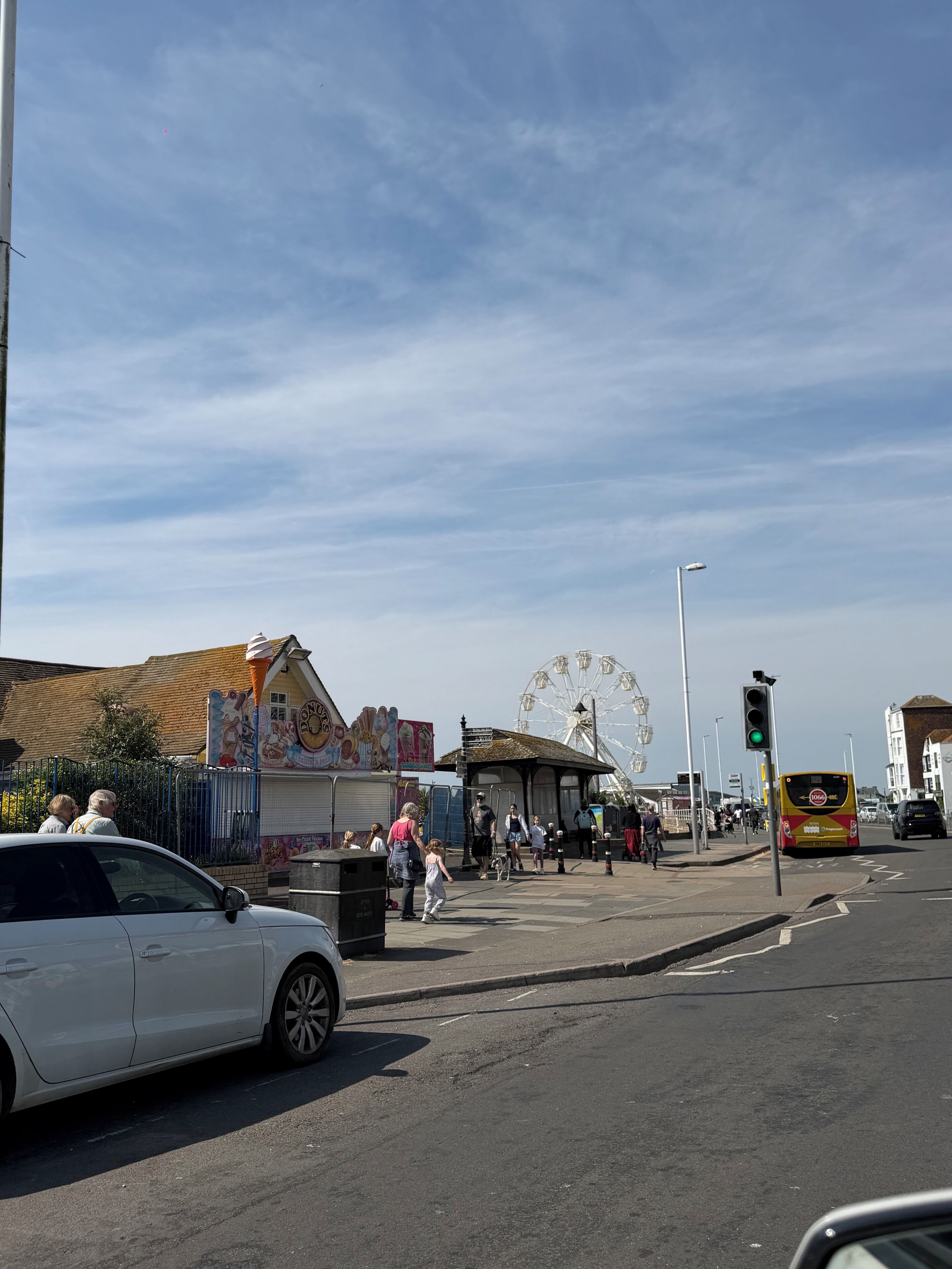 A street with a Ferris wheel, a bus, and a building with a mural.