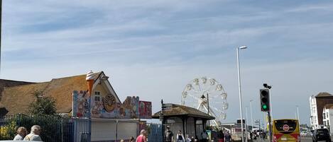 A street with a Ferris wheel, a bus, and a building with a mural.
