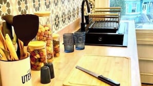 Una cocina con encimera de madera, tabla de cortar, cuchillo, especiero y cafetera.