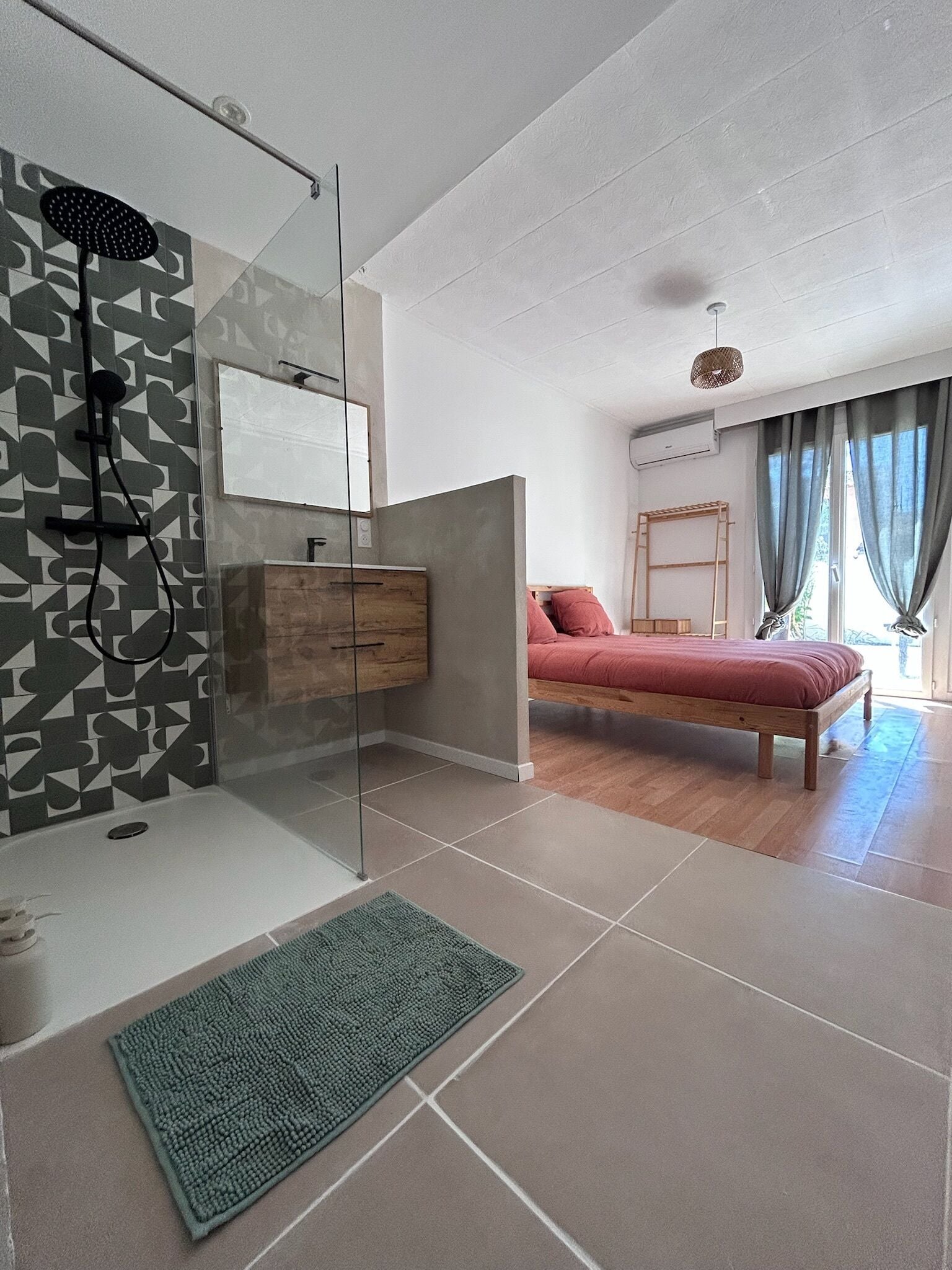 Ein modernes Schlafzimmer mit Dusche, einem hölzernen Bett, einem Nachttisch und einem Fenster mit Vorhängen.