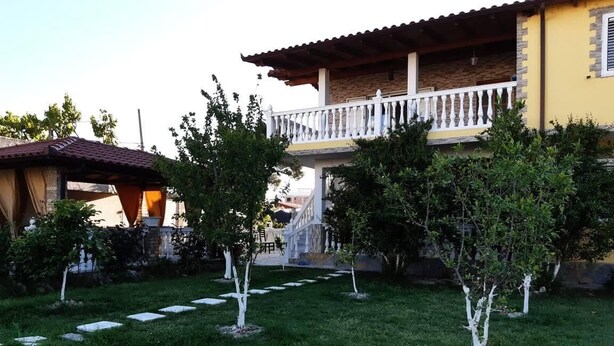 A building with a balcony, a garden with stepping stones, and a pathway.
