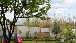 A backyard with a play area, including a slide, a tree, and a white fence.