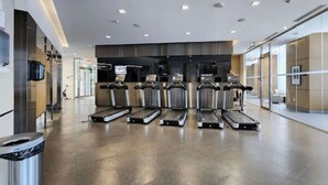 Ein modernes Fitnessstudio mit Laufbändern, einem Wandfernseher und einem Papierkorb.