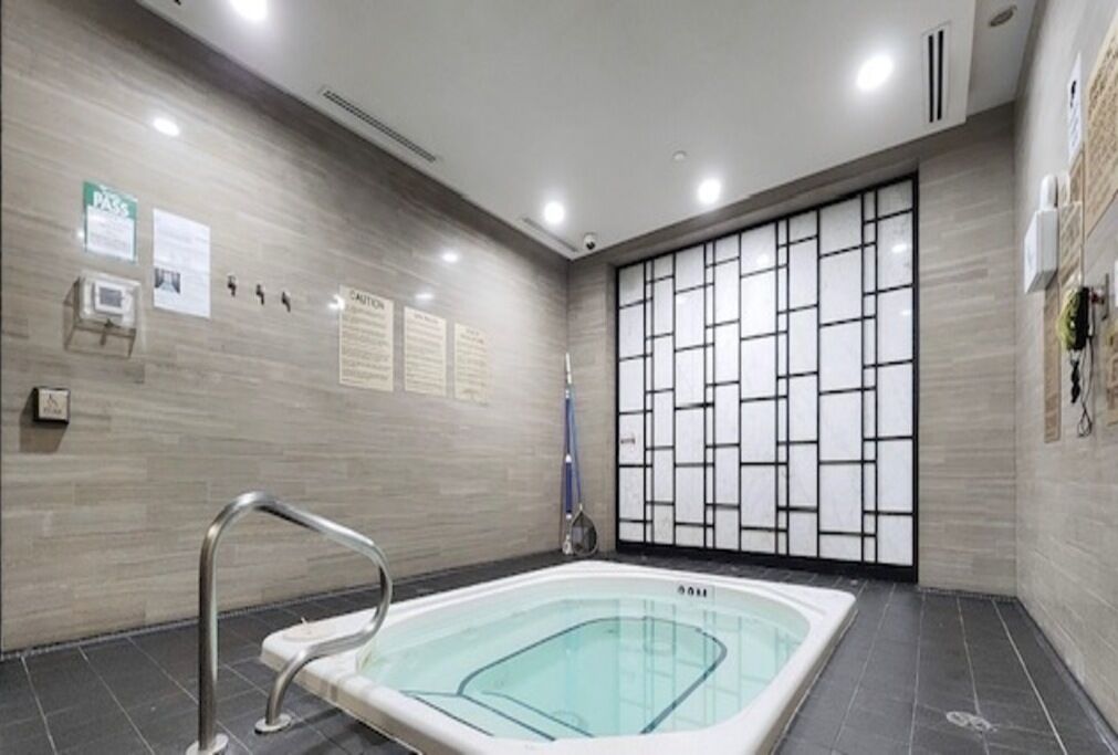 A modern indoor pool with a glass enclosure, a metal handrail, and a tiled floor.