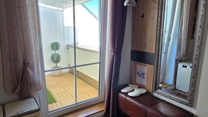A room with a sliding glass door, a wooden bench, a mirror, and a small plant. - Apartment with high-quality furnishings and underground parking space in Burghausen. (Burghausen)