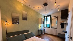Ein Schlafzimmer mit einem Bett, zwei Wandleuchten, einem Fenster mit Blick, einem Heizkörper und einem Spiegel.