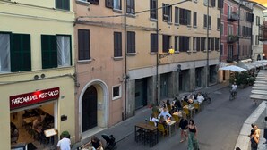 A street with outdoor seating, a restaurant named 'Farina del Mio Sacco,' and buildings with multiple stories and balconies. - Ancient Street - Historic Center (Ferrara)