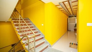 A staircase with a handrail leading to a landing, a door at the top, and a bright yellow wall. - Hotel Ram Janaki (Janakpur)