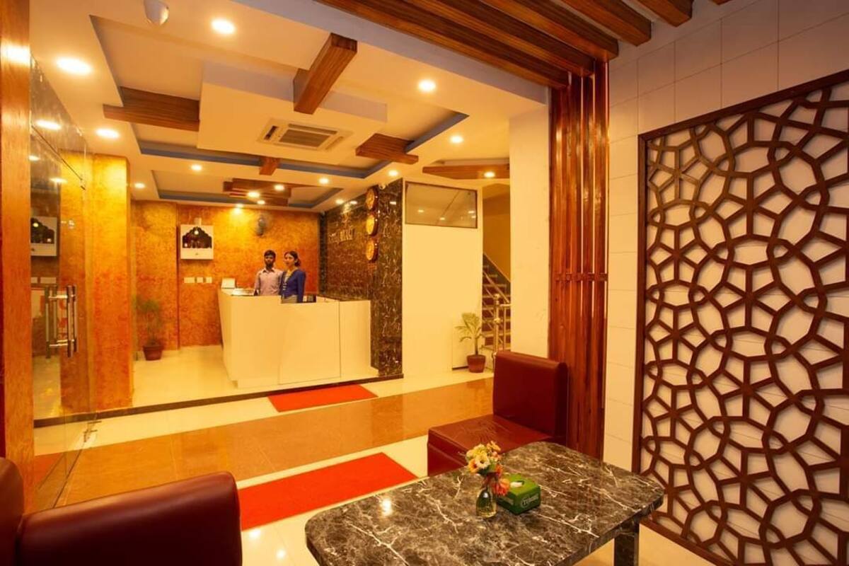 A reception area with a marble counter, wooden ceiling beams, and a decorative wall panel.