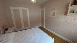 Une chambre à coucher comprenant un lit, une armoire, un miroir et une étagère sur laquelle est posée une figurine.